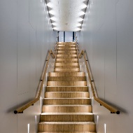 Eine mit Parkett verkleidete Treppe führt in das Obergeschoss und hebt sich optisch eindrucksvoll von den weissen Wänden und Decken ab.