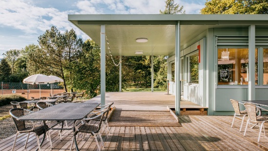 Hellgrüner Sportfeldpavillon mit Terrasse und Sitzmöbeln