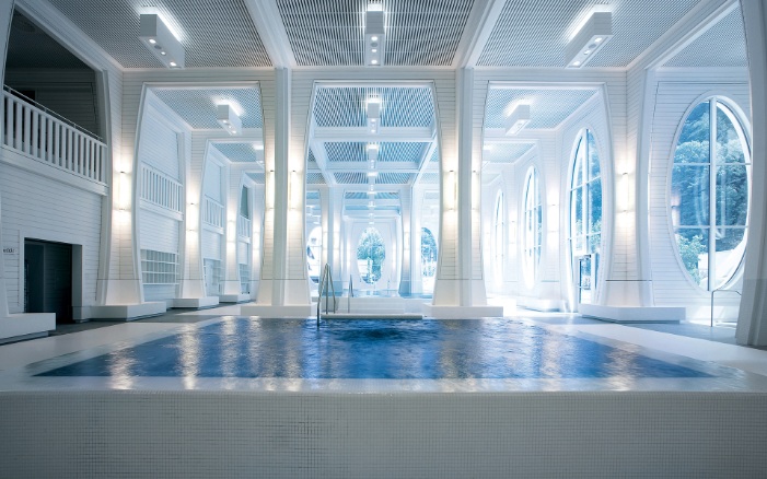 Swimming pool in a room with white columns and wooden ceiling cladding