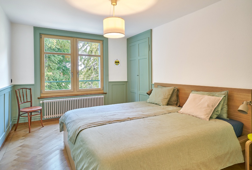 Schlafzimmer mit Holz-Fussboden und hellgrünen Akzenten<br/><br/>